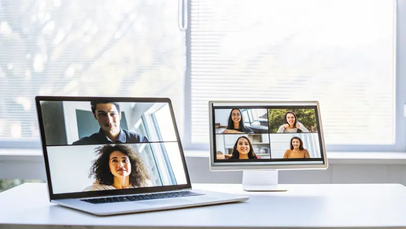Multiple computer screens showing virtual conference participants in video call grid